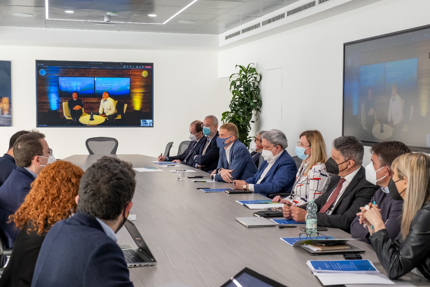 A group of people sitting at a table looking at a screen Description automatically generated with medium confidence